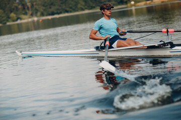Sportsman single scull man rower rowing on boat. Paddle splash movement - obrazy, fototapety, plakaty