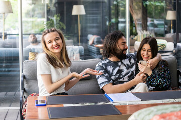 Beautiful lady sitting with young couple and point her hands to them
