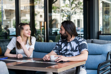 Fototapeta premium \Young couple sitting at the cafe and looking at each other