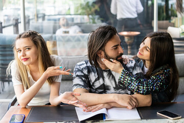 Beautiful lady sitting with her friends and pointing hand at them