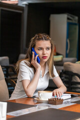 Vertical photo of young lady sitting at the restaurant and talking on the phone