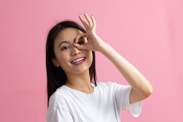 Fototapeta premium Portrait of asian woman with ok gesture on pink background.