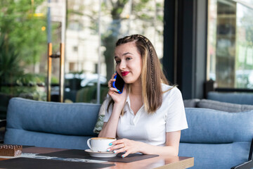 Young girl sitting at the restaurant and talking on the phone