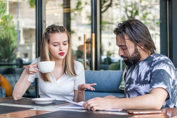 Fototapeta premium Sweet girl drinking coffee and talking with young man at the restaurant
