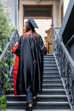 Peaceful student wearing peace graduation cape and standing on the stairs