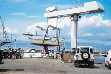 A boat lifted by a crane on the quay of the port of Thonon les Bains on Lake Leman