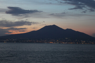 Fototapeta na wymiar Mount Vesuvius, near Naples (last erupted in 1944); the only volcano to have recently erupted in Continental Europe image shows the volcano across the sea with a beautiful sunset. August 2022