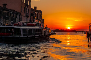 Canal à Venise au coucher du soleil avec un vaporetto. 