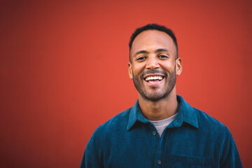 Handsome man laughing over maroon bacckground