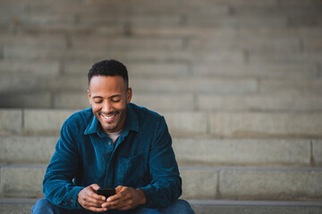 Obraz premium Smiling man text messaging using mobile phone