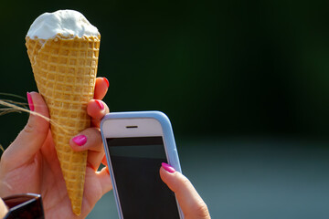 A large phone and ice cream in a waffle cone are shown