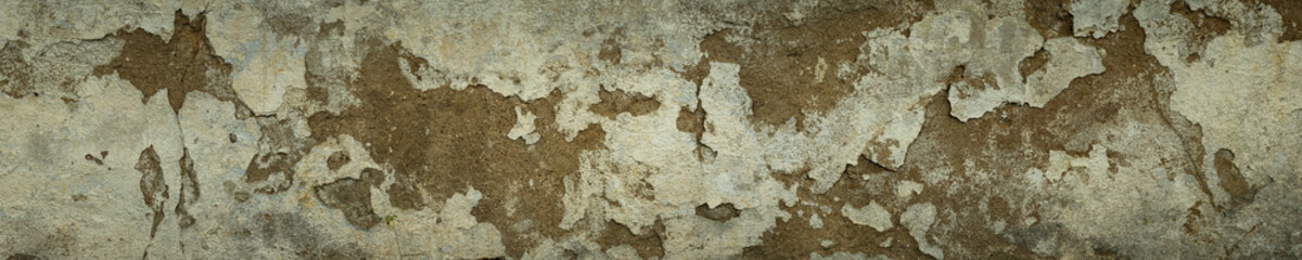 widescreen gray-brown background of an ancient abandoned wall with pieces of old cement plaster for creative design or brutal backdrop