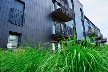 Modern architecture, residential area with modern apartment building with black facade and green grass
