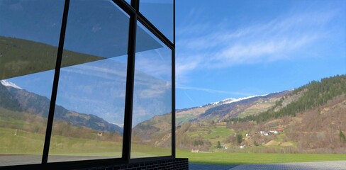 The stunning mountain scenery is reflected on the glass facade of a modern, newly built home. 3d render.