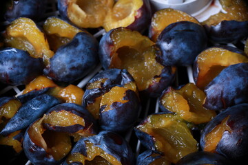 halves of plums are laid out on a tray for drying