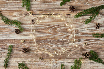 Christmas composition with fir tree branches and lighting garland on wooden background. Christmas frame, flat lay. Xmas greeting banner with copy space