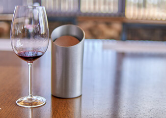 wineglass and a metal spittoon on a wooden table at a wine tasting. Indoors, Selective focus.