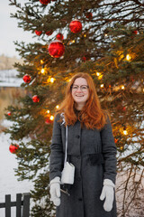 woman is resting and walking in the park in winter, a happy European woman with red hair is skating. a young and beautiful woman in a gray vintage coat is enjoying the Christmas holidays