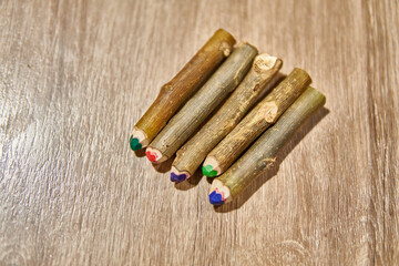 HANDMADE RUSTIC COLORED CRAYONS PENCIL OVER A WOODEN TABLE. MADE OF NATURAL WOOD TRUNK. TOP VIEW