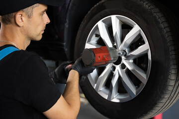 Assembly or dismantling of the wheels in the workshop. repair and maintenance of the car in service. Car mechanic replacing car wheel of lifted automobile at repair service station