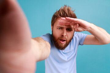 Portrait of young adult handsome curious bearded man looking into distance with attentive view,...