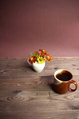 cup of coffee with orange  flowers cup of coffee on brown wooden table