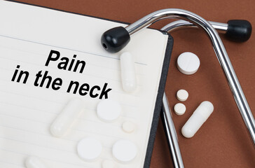 On a brown surface lies a stethoscope, pills and a notepad with the inscription - Pain In The Neck