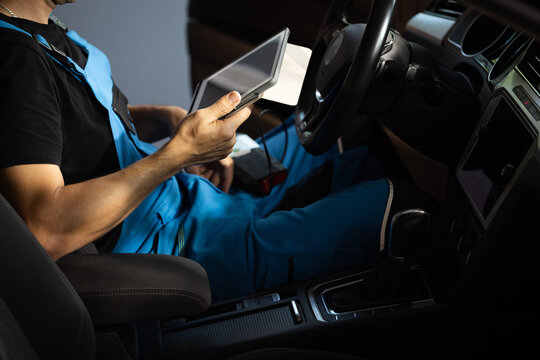Car mechanic maintains the vehicle with the help of diagnostic modern computer equipment. Car service manager uses tablet computer with diagnostics software