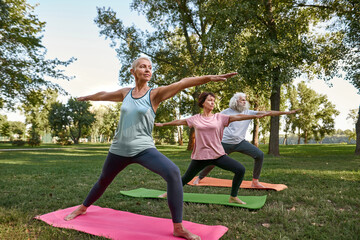 Middle aged people practicing warrior yoga pose