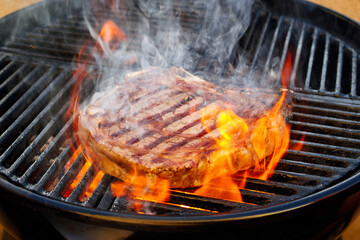 Barbecue dry aged Wagyu cote de boeuf steak grilled as close-up on a charcoal grill with fire and smoke