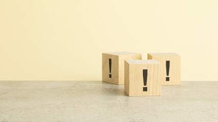 exclamation marks are written on wooden blocks. Blocks are located on a yellow background