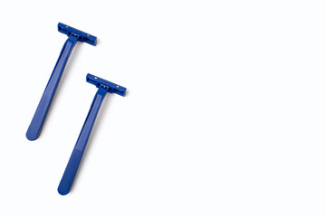 Two blue plastic razors are located on a white background. Disposable blue plastic razors lie on a white background. Free space for text or advertising. Shaving and smooth skin care