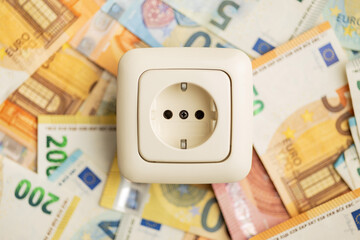 Electric wall socket and euro money. Concept of increasing electricity prices.