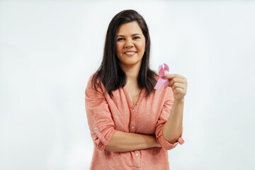 Young Brazilian woman holding breast cancer ribbon over white background