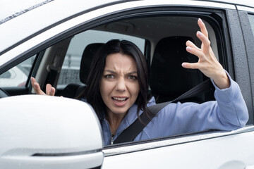 Portrait of a Shocked and aggressive talking young woman, driver inside a car. Concept Road trip Insurance accident.