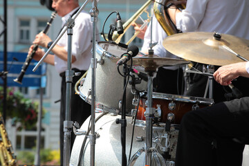 A group of professional musicians on stage playing drums and wind instruments into a microphone...