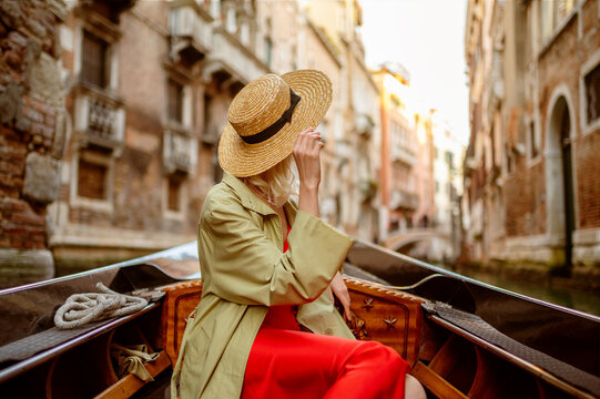 Fototapeta Rear, back view of elegant woman wearing straw hat on Gondola ride along beautiful street in Venice, Italy. Travel, vacation, lifestyle conception. Copy, empty space for text