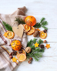 Obraz na płótnie Canvas Knitted sweater, citrus fruits, dry orange slices, fir branches, cones and heart card on wooden table close up. Festive winter seasonal background. top view