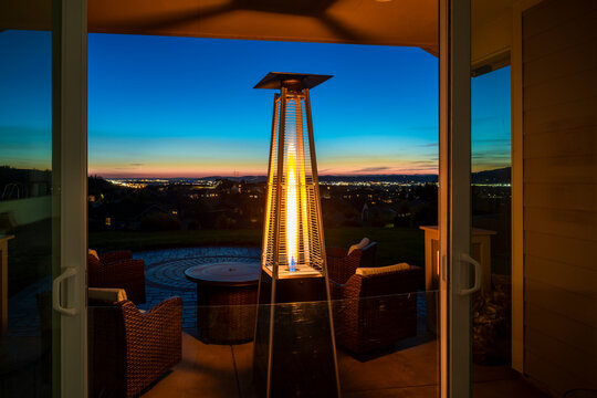 View from a hillside home's outdoor back patio with flame heater of the cities of Spokane and Spokane Valley at sunset.
