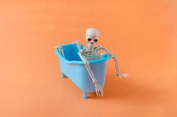 A skeleton taking a bath in a blue bath tube. Halloween party invitation concept. Funny and spooky...