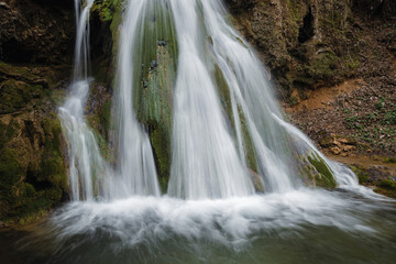 Fototapeta na wymiar Beautiful waterfall splashing over mossy rocks