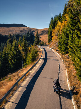 Vertical shot of Transbucegi road, where a motorcycle driver is driving on a sunny day