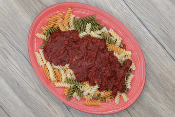 Overhead view of rotelli pasta smothered in authentic Italian marinara sauce and generously served on an oval plate