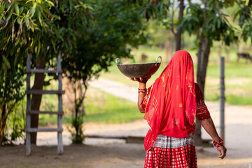 Woman carrying cauldron in Indian village - 526856468