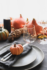 Thanksgiving day dinner decorated pumpkins and fallen leaves on gray linen tablecloth. Close up....