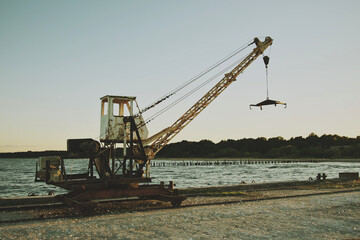 Old rusty Crane on the pier. Old vintage winch for lifting boats. Old movie style.