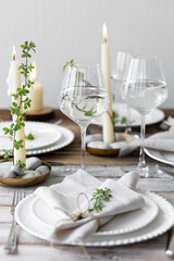 Rustic zero waste wedding decor with natural elements. Wooden table, candles, linen napkins, branches with green leaves. Eco-friendly decoration for the special dinner. Romantic and cozy place