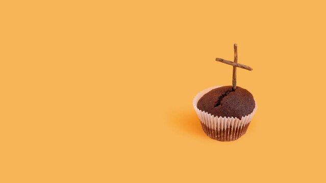 Minimal Halloween concept with muffin and wooden cross on orange background 4k.