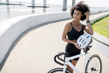 Fototapeta na wymiar A woman uses a bicycle eco transport in the city, fitness cardio training, holds a helmet