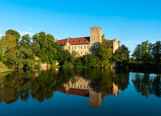 Naklejka na ściany i meble Flechtingen, Germany - August 8, 2022: Historical moated medieval castle of Flechtingen, Saxony-Anhalt, Germany, and its reflection in the pond in the golden hour.